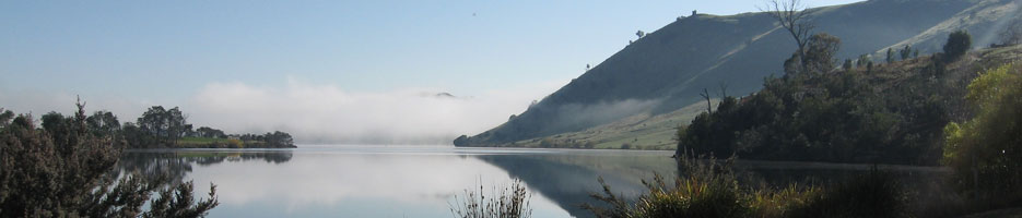 A lake, with a reflection of a nearby hill reflected on the surface.